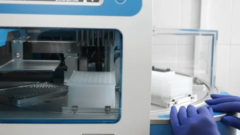 Hands inserting tray into nucleic acid extraction station in PCR laboratory. Видео 321576465
