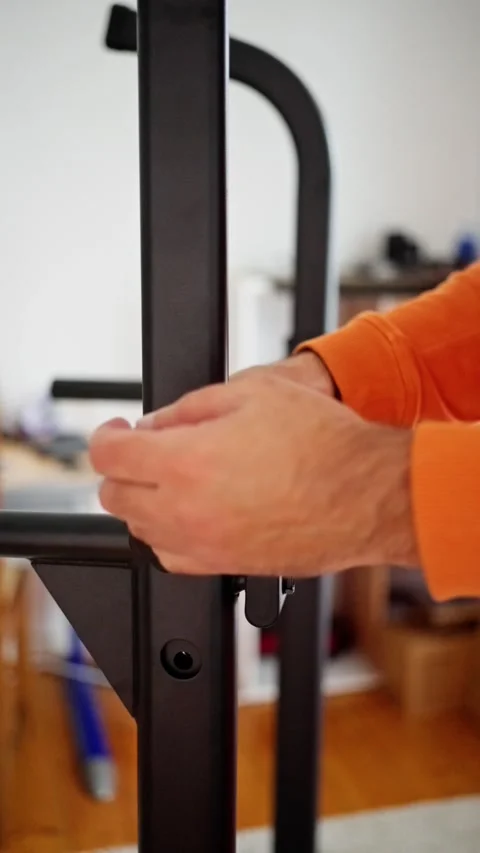 Hands install safety gate latch indoors with plastic knob, orange-sleeve Stock Footage 321302557
