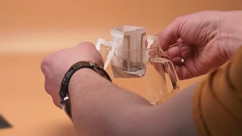 Hands install single serve coffee drip bag on a glass server Stock Footage 195524108