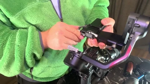 Hands installing camera mount on stabilizer close-up, attaching plate to gimbal Stock Footage 333649569
