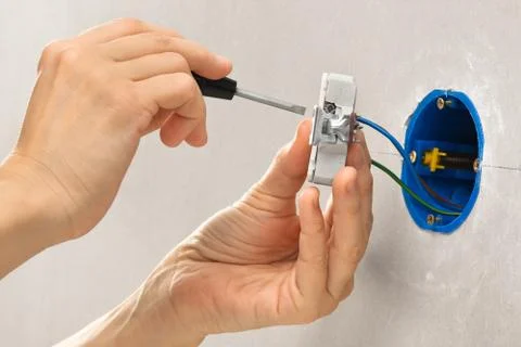 Hands installing electrical wall socket with screwdriver Stock Photos