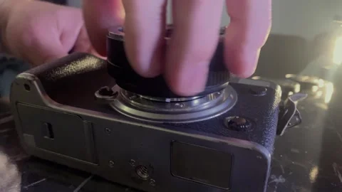 Hands installing lens adapter onto camera bayonet mount close-up, aligning metal Stockbeeldmateriaal 333650325