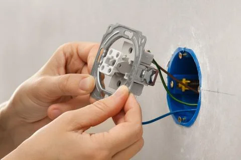Hands installing light switch in plasterboard wall Stock Photos