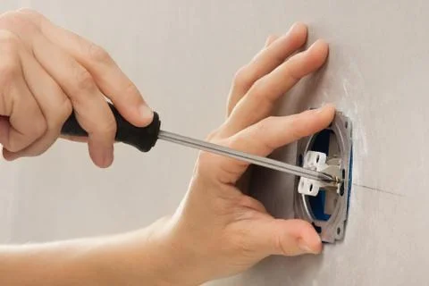 Hands installing light switch with screwdriver Stock Photos