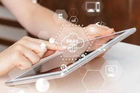 Hands interact with a tablet displaying SaaS icons and cloud symbols in a Foto stock