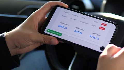 Hands interact with a travel expense tracker in a parked car, showing a moment Stock-Footage 316765945