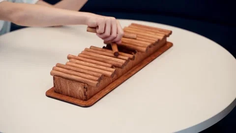Hands interact with a wooden board game on a table, arranging sticks Stock Footage 322975968