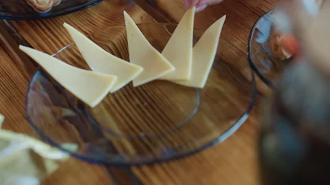 Hands Interacting With Cheese Slices On Glass Plate Over Wooden Table Vídeo Stock 316837270