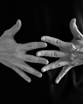 Hands intertwined in a gesture of complexity on a dark background Фото