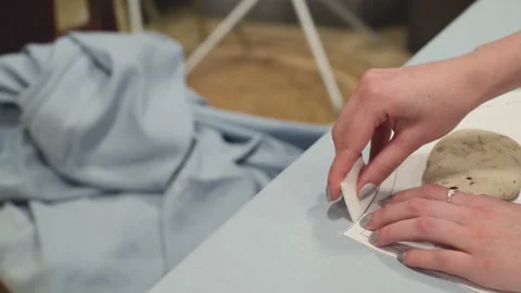 Hands iron fabric on a table. Fabric is light blue and wrinkled. Iron glide.. Stock Footage 340040063