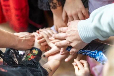 Hands joining together in a circle during a community gathering celebrating Stock Photos