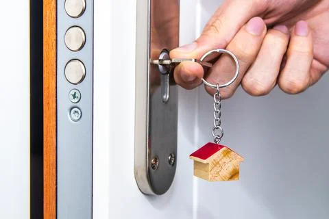 Hands with keys in the door lock Stock Photos