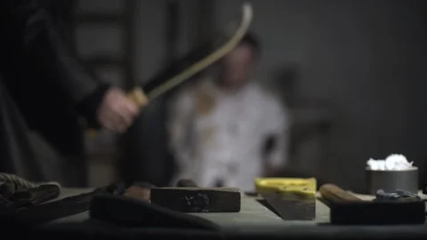 Hands of killer takes machete from table and comes to tied hostage, cuts victim. Stock Footage 86283283