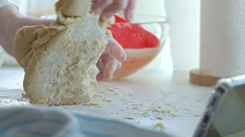 Hands knead dough on floured kitchen counter with baking tools nearby Stock Footage 334329561