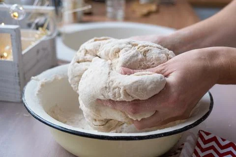 Hands knead thick dough on the kitchen table, decorated with festive decora.. Foto stock