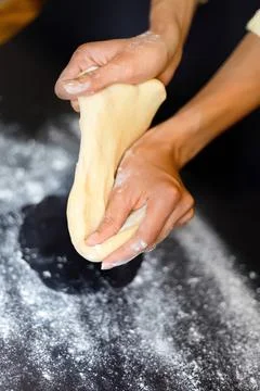 Hands kneading dough on a floured surface for baking Stock Photos