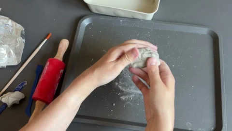Hands kneading gray clay into a smooth ball for a handmade autumn pumpkin craft Stock Footage 345719071