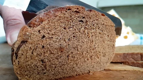 Hands knife cut dark bread on wooden board slow-motion shot Stock Footage 90065419