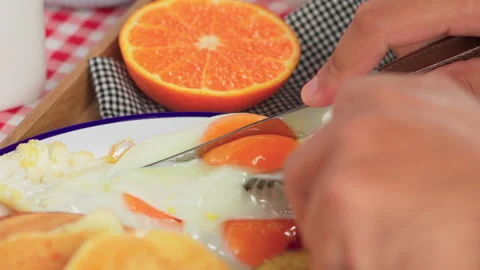 Hands knife cut fried egg on breakfast platter Stock Footage 158432435