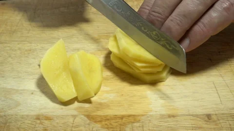 Hands with a knife cut raw potatoes in slow motion. Video stock 133069880