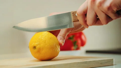 Hands with knife cutting lemon on the kitchen board Stock Footage 153474704