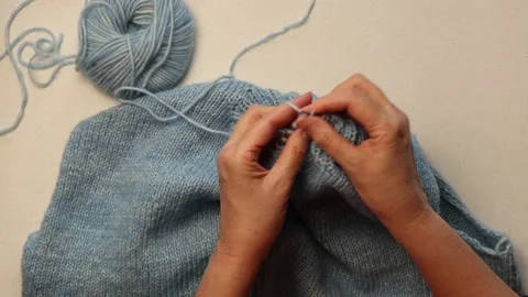 Hands knitting a sweater of blue wool yarn with knitting needles Stock Footage 170717389