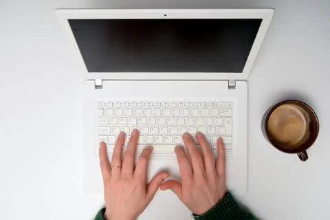 Hands on laptop computer keyboard at white desk. High angle overhead view Stock Photos