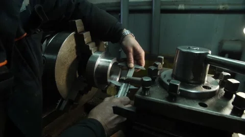 Hands of lathe operator in uniform measuring metal part with caliper Stock Footage 158051011