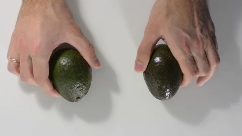 Hands lay two green ripe avocados on a white table close-up Stock Footage 122557421