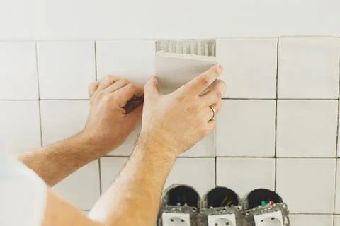 Hands laying modern square tile on adhesive close up. Worker installing sty.. Stock Photos