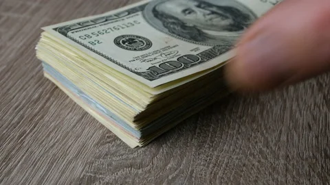 Hands leaf through many dollars in stack on wooden table. Stock Footage 125458735