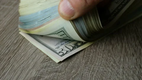 Hands leaf through many dollars in stack on wooden table. One banknote after Stock Footage 153626288