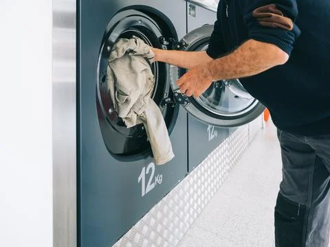 Hands to load the Laundry in the washing machine at the dry cleaners 写真素材