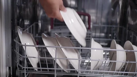 Hands loading dirty plates into dishwasher for cleaning. Vidéo 333023575
