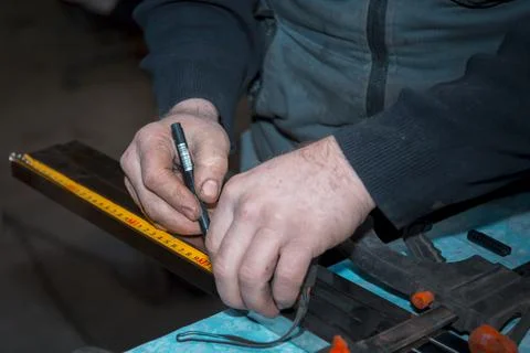 The hands of a locksmith mark out a stainless profile pipe 스톡 사진
