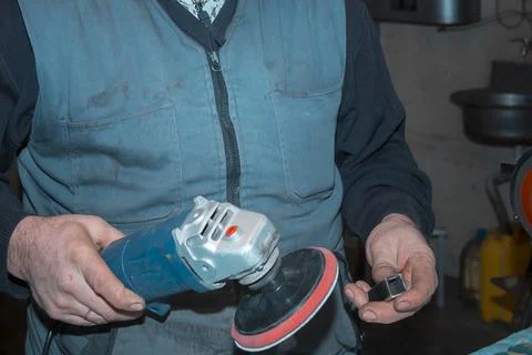 The hands of a locksmith process the part with a grinder 스톡 사진