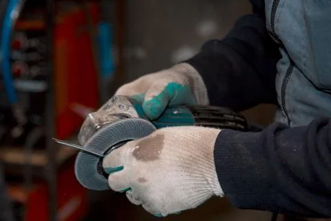 The hands of a locksmith process the part with a grinder Fotos Stock