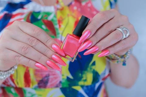 Hands with long nails and bright neon pink red nail polish 스톡 사진