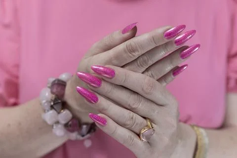 Hands with long nails and bright neon pink red nail polish 스톡 사진