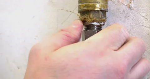 Hands loosening pipe connection on wall with effort Stock Footage 302339714