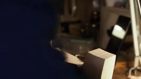 Hands of luthier work on raw violin scroll under a small lamp in Cremona, using Stock Footage 304641739