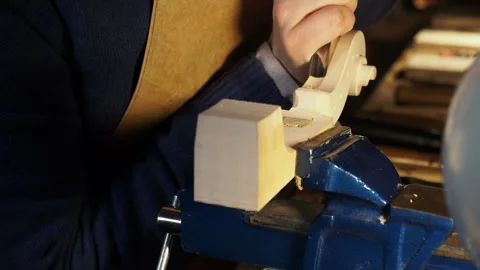 Hands of luthier work on raw violin scroll under a small lamp in Cremona, using Stock Footage 304641854