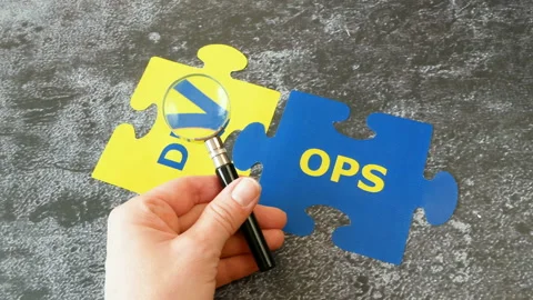 Hands with magnifier glass with words Dev and Ops puzzles. Concept for softwa Stock Footage 146474827