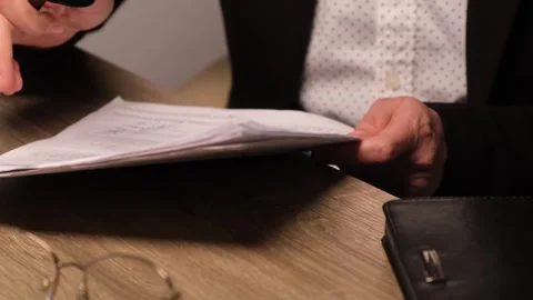 Hands with magnifying glass examining documents or contract before signing or Stock Footage 311386577