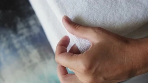 Hands of maid putting stack of fresh clean white bath towels on the bed Stock Footage 217779220
