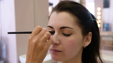 Hands make-up artist applied makeup on the face of a young woman. Girl doing eye Vidéo 107180307