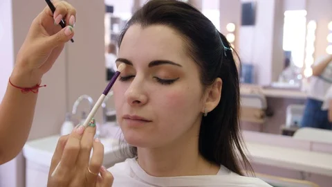 Hands make-up artist applied makeup on the face of a young woman. Girl doing eye Vidéo 107180801