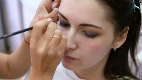 Hands make-up artist applied makeup on the face of a young woman. Girl doing eye Vidéo 107181272