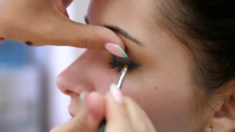 Hands make-up artist applied makeup on the face of a young woman. Girl doing eye Vídeo Stock 107181324