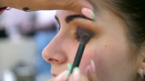 Hands make-up artist applied makeup on the face of a young woman. Girl doing eye 库存影片 107182689